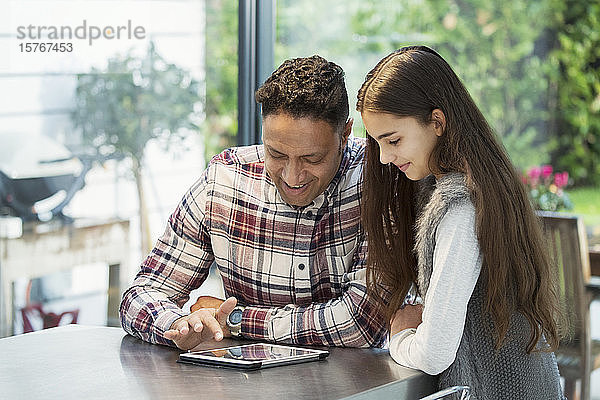 Vater und Tochter benutzen ein digitales Tablet in der Küche