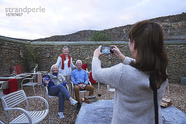 Frau mit Fotohandy fotografiert ältere Freunde auf der Veranda