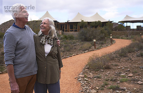 Glückliches Seniorenpaar auf dem Fußweg vor der Safari-Lodge