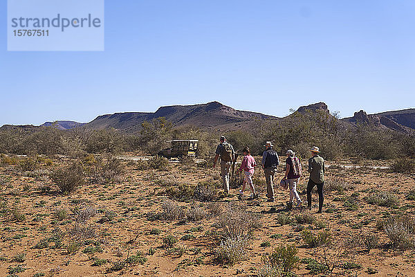 Safari-Gruppe auf dem Rückweg zum Geländewagen im sonnigen Wildschutzgebiet