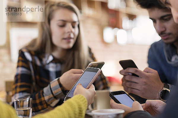 Freunde junger Erwachsener benutzen Smartphones im Café