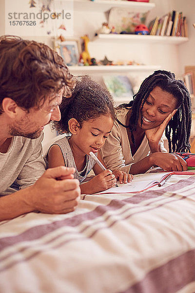 Junge Familie beim Malen auf dem Bett