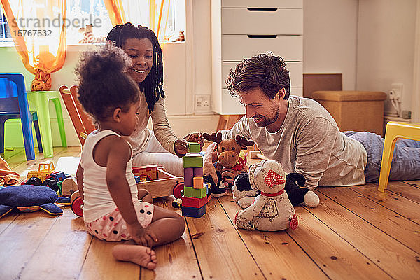 Junge Familie spielt mit Spielzeug auf dem Boden
