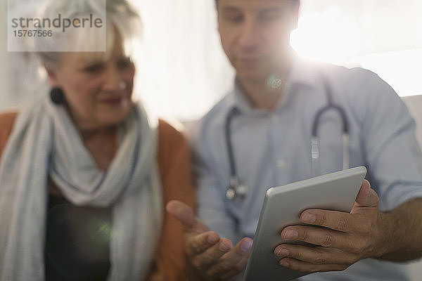 Männlicher Arzt zeigt einem Patienten ein digitales Tablet