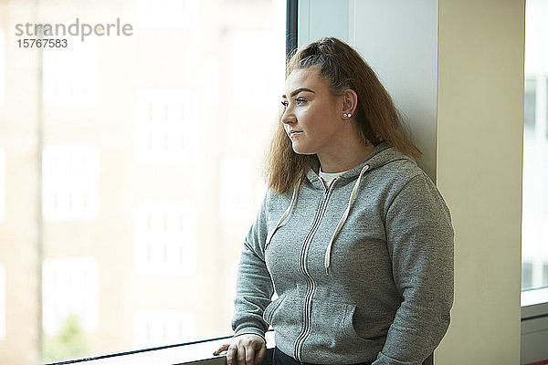 Nachdenkliches Teenager-Mädchen schaut aus dem Fenster