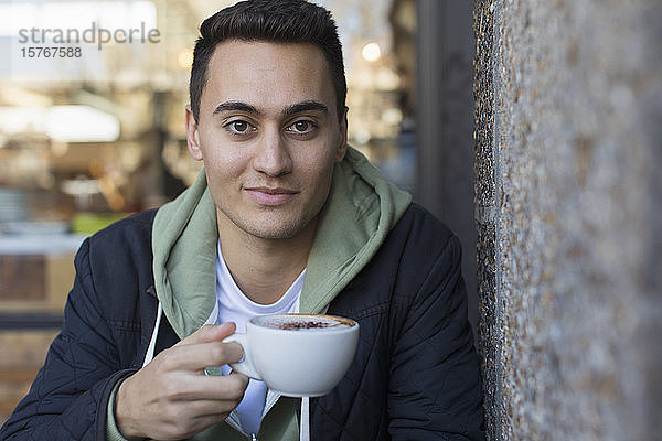 Porträt selbstbewusster junger Mann trinkt Cappuccino