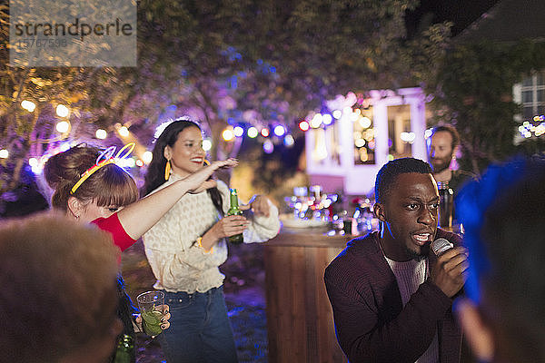Freunde trinken und singen Karaoke auf einer Party