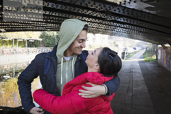 Glückliches  zärtliches junges Paar  das sich unter einer städtischen Brücke umarmt