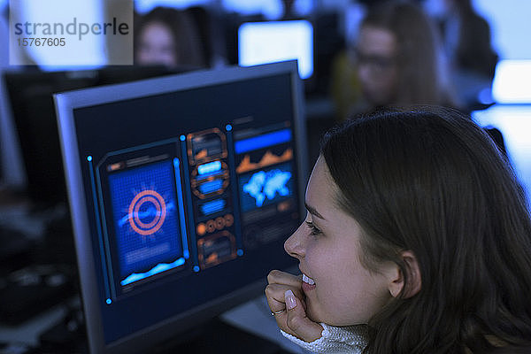 Lächelnde Schülerin der Junior High  die einen Computer im Computerraum benutzt