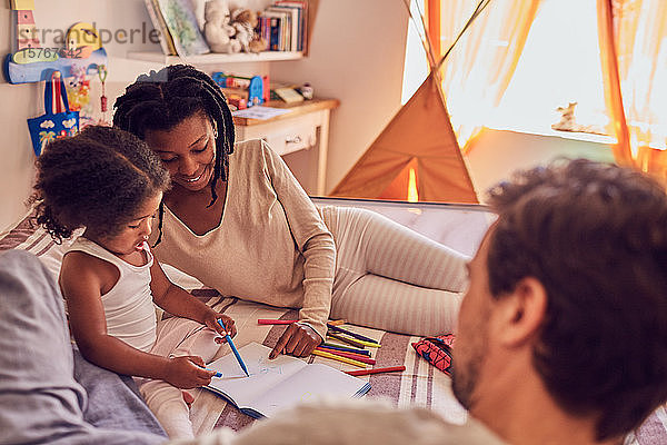 Junge Familie beim Malen auf dem Bett