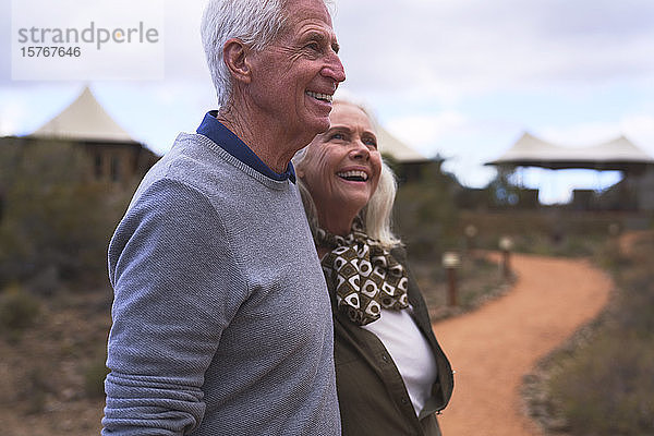 Glückliches Seniorenpaar auf dem Fußweg vor der Safari-Lodge
