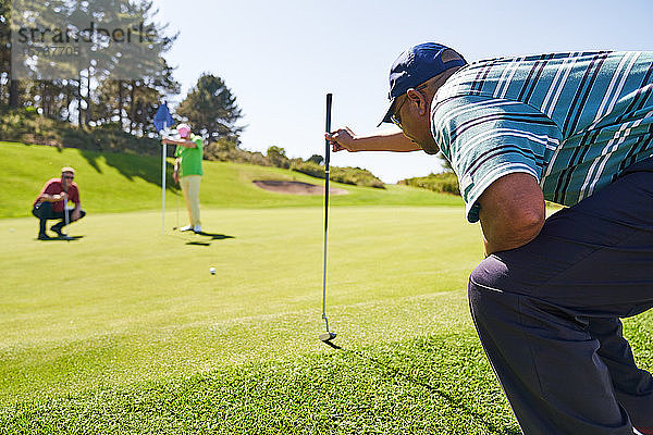 Männlicher Golfer bereitet sich auf dem sonnigen Golfplatz auf den Putt vor