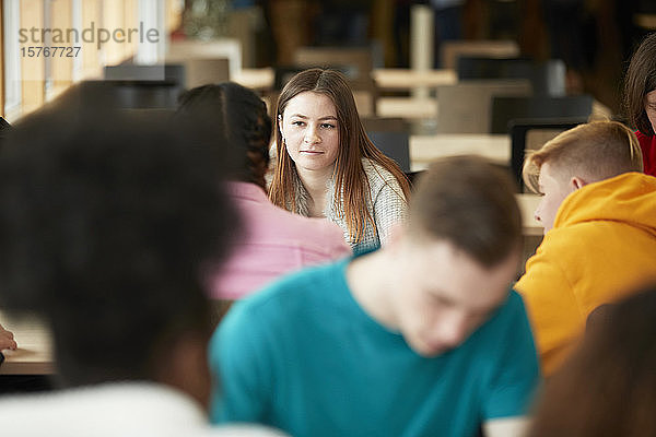 Junge Studentin hört einem Klassenkameraden zu