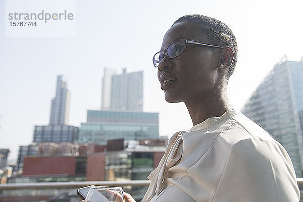 Ehrgeizige  selbstbewusste Geschäftsfrau auf sonnigem  städtischem Balkon