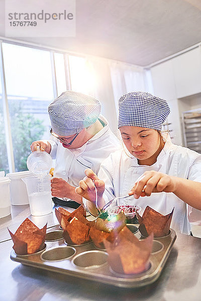 Junge Schüler mit Down-Syndrom backen Muffins in der Küche
