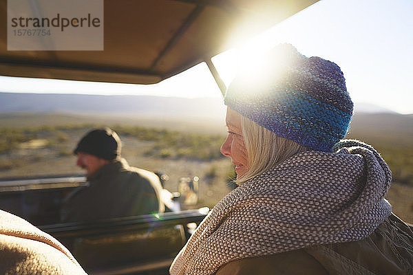 Glückliche ältere Frau fährt in sonnigem Safari-Geländewagen