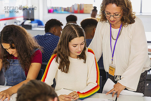 Gymnasiallehrerin hilft Schülerin bei den Hausaufgaben im Klassenzimmer