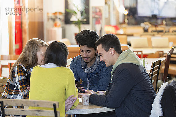 Junge Freunde benutzen Smartphones am Kaffeetisch