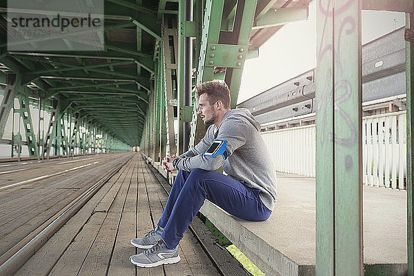 Junger männlicher Läufer  der sich auf dem Bahnsteig einer S-Bahn-Station ausruht