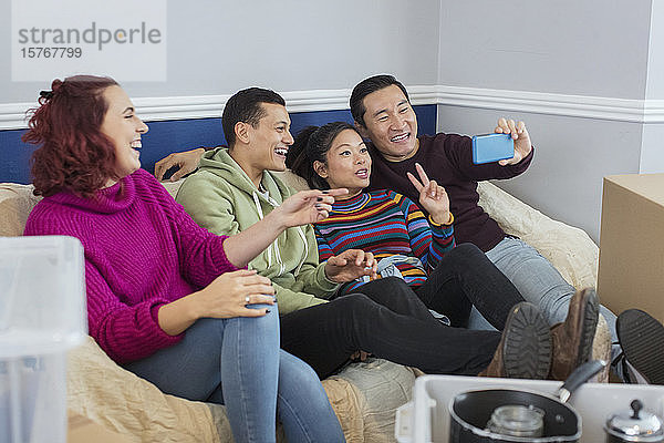 Glückliche Freunde machen eine Pause vom Umzug und machen ein Selfie auf dem Sofa