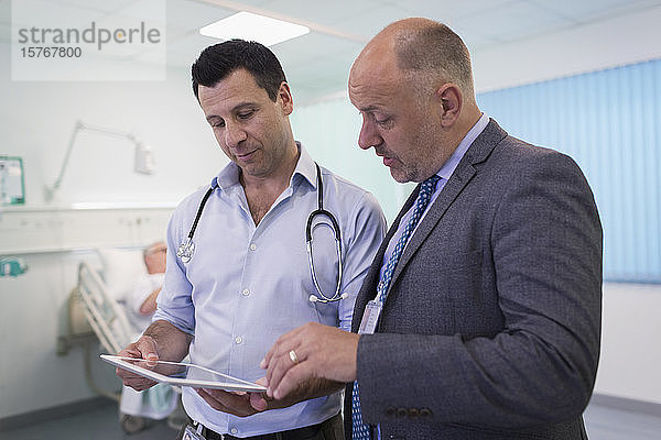 Männliche Ärzte mit digitalem Tablet bei der Visite  Beratung im Krankenhauszimmer