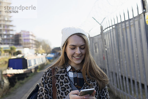 Junge Frau benutzt Smartphone am Kanal