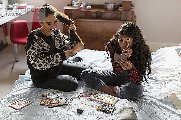 Teenager-Mädchen tragen Make-up auf und bürsten sich die Haare im Bett