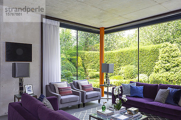 Modernes Wohnzimmer mit lila Möbeln und Blick auf den sonnigen Garten