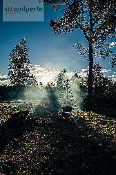 Erhitzen von Töpfen über dem Lagerfeuer in sonnigen  ruhigen Wäldern