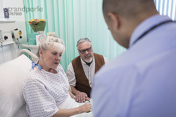 Arzt auf Visite  Gespräch mit älterem Ehepaar im Krankenhauszimmer