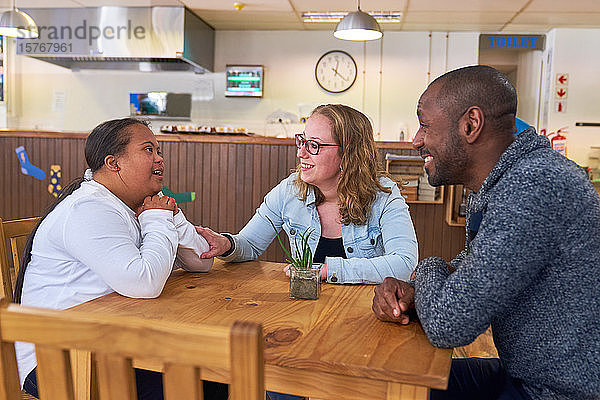 Eltern und Tochter mit Down-Syndrom unterhalten sich in einem Cafe