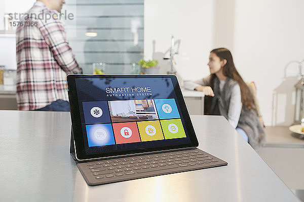 Vater und Tochter in der Küche hinter einem intelligenten Hausautomatisierungssystem auf einem digitalen Tablet