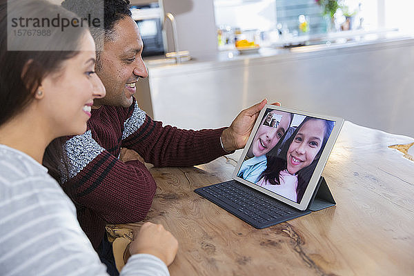 Ehepaar führt Videokonferenzen mit Töchtern über ein digitales Tablet in der Küche durch