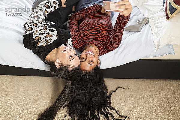 Glückliche Teenager-Mädchen nehmen Selfie mit Smartphone auf dem Bett
