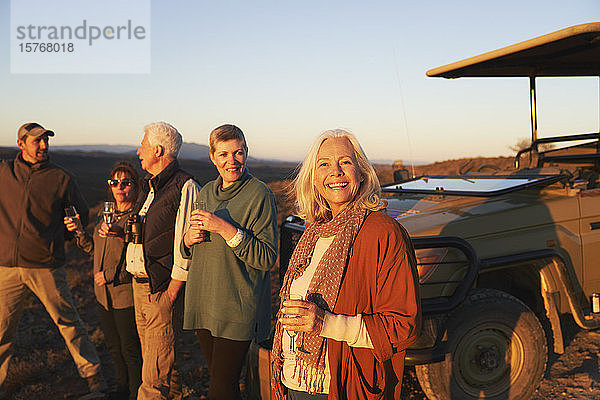 Porträt glückliche ältere Frau auf Safari trinkt Champagner mit Freunden