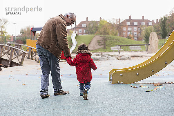 Großvater geht mit Kleinkind-Enkel auf Spielplatz