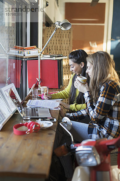Junge Studentinnen studieren im Fenster eines Cafés