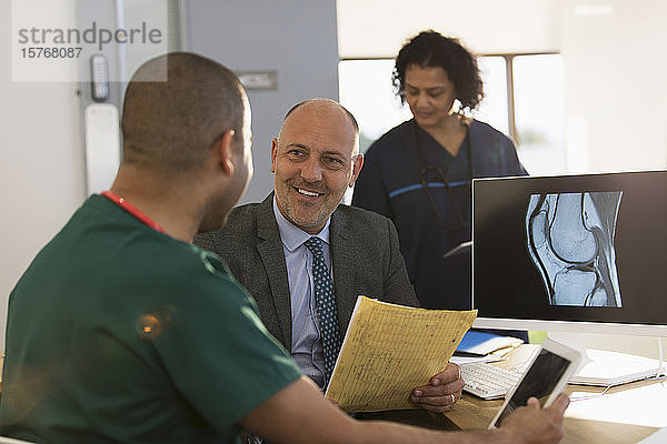 Arzt und Krankenschwester besprechen ein digitales Röntgenbild am Computer in einer Klinik