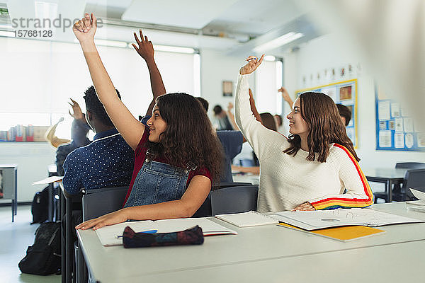Gymnasiastinnen mit erhobenen Händen während des Unterrichts im Klassenzimmer