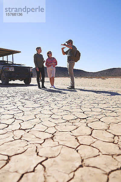 Safari-Führer im Gespräch mit einem Paar in der sonnigen Wüste