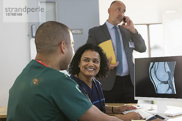 Lächelnde Krankenschwestern besprechen digitale Röntgenbilder am Computer in der Klinik
