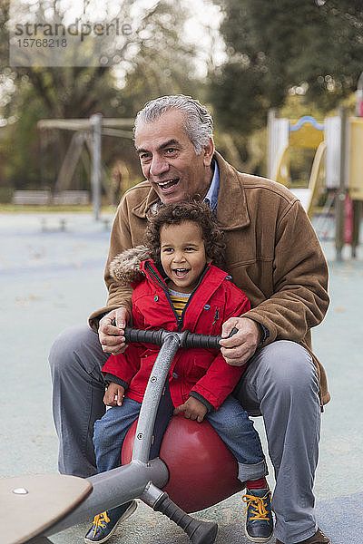 Großvater spielt mit Enkel auf Spielplatzwippe