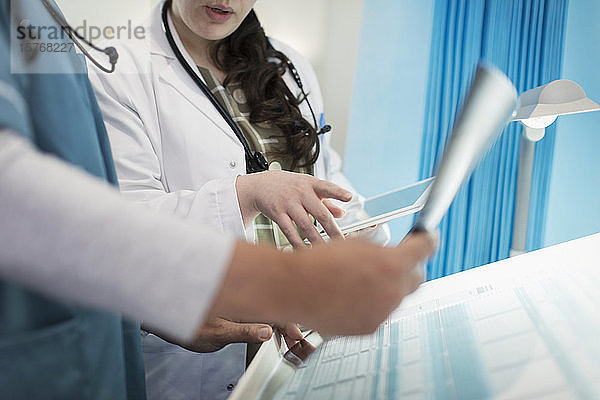 Ärzte mit digitalem Tablet bei der Besprechung von Röntgenaufnahmen in einem Krankenhauszimmer