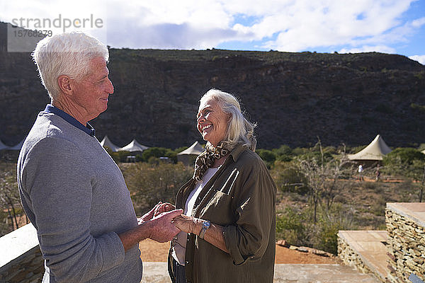 Glückliches älteres Paar auf dem sonnigen Balkon einer Safari-Lodge in Südafrika