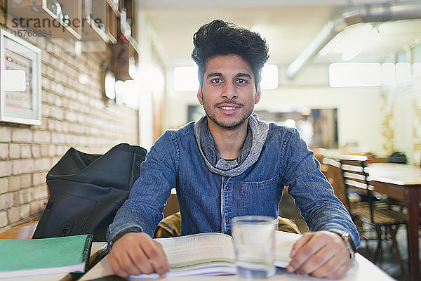 Porträt selbstbewusster junger männlicher Student  der in einem Café lernt