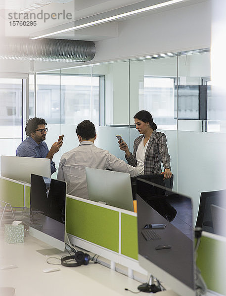Geschäftsleute mit Smartphones treffen sich in einem Großraumbüro