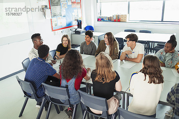 Gymnasiasten unterhalten sich im Debattierkurs am Tisch im Klassenzimmer