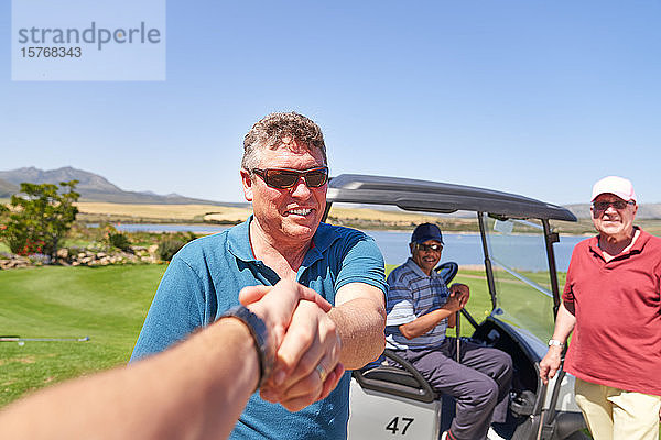 Persönliche Perspektive männliche Golfer beim Händeschütteln auf dem sonnigen Golfplatz