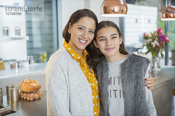 Porträt glückliche Mutter und Tochter  die sich in der Küche umarmen