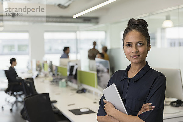 Porträt einer selbstbewussten Geschäftsfrau mit digitalem Tablet in einem Großraumbüro